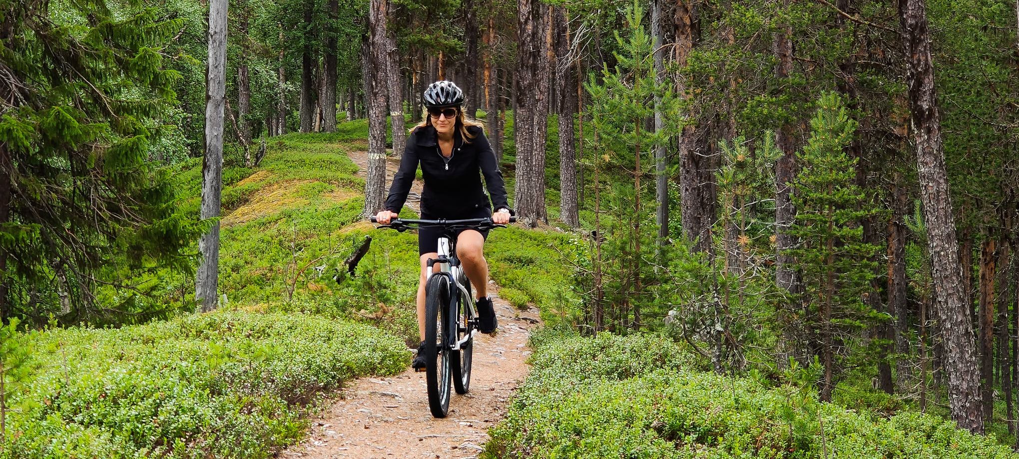 En kvinna cyklar på en mounten bike längs en stig.