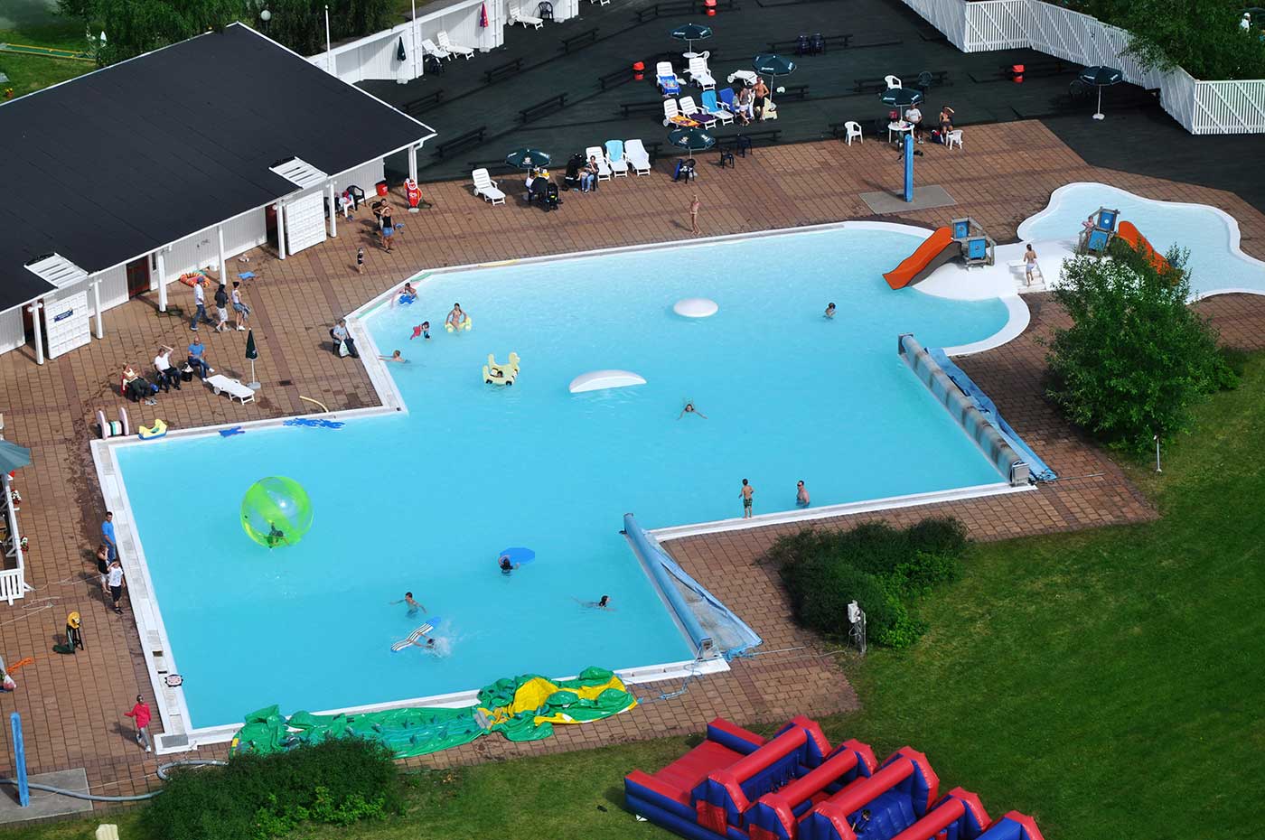 Flygfoto över en utomhus pool där människor badar.